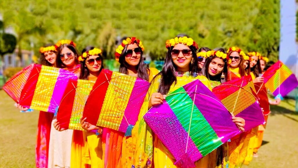 Women in vibrant saris joyfully hold colorful kites, embodying the festive spirit of a Basant-themed celebration.